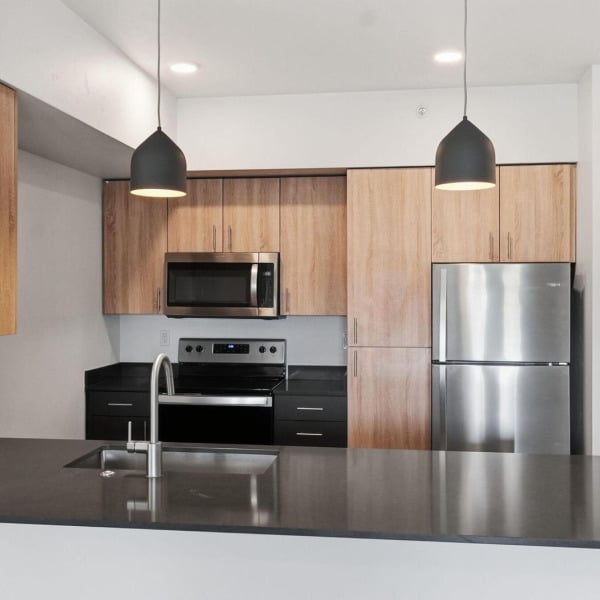 Modern kitchen with stainless steel appliances and wood cabinetry in an apartment home at Cypress in Redmond, Oregon.