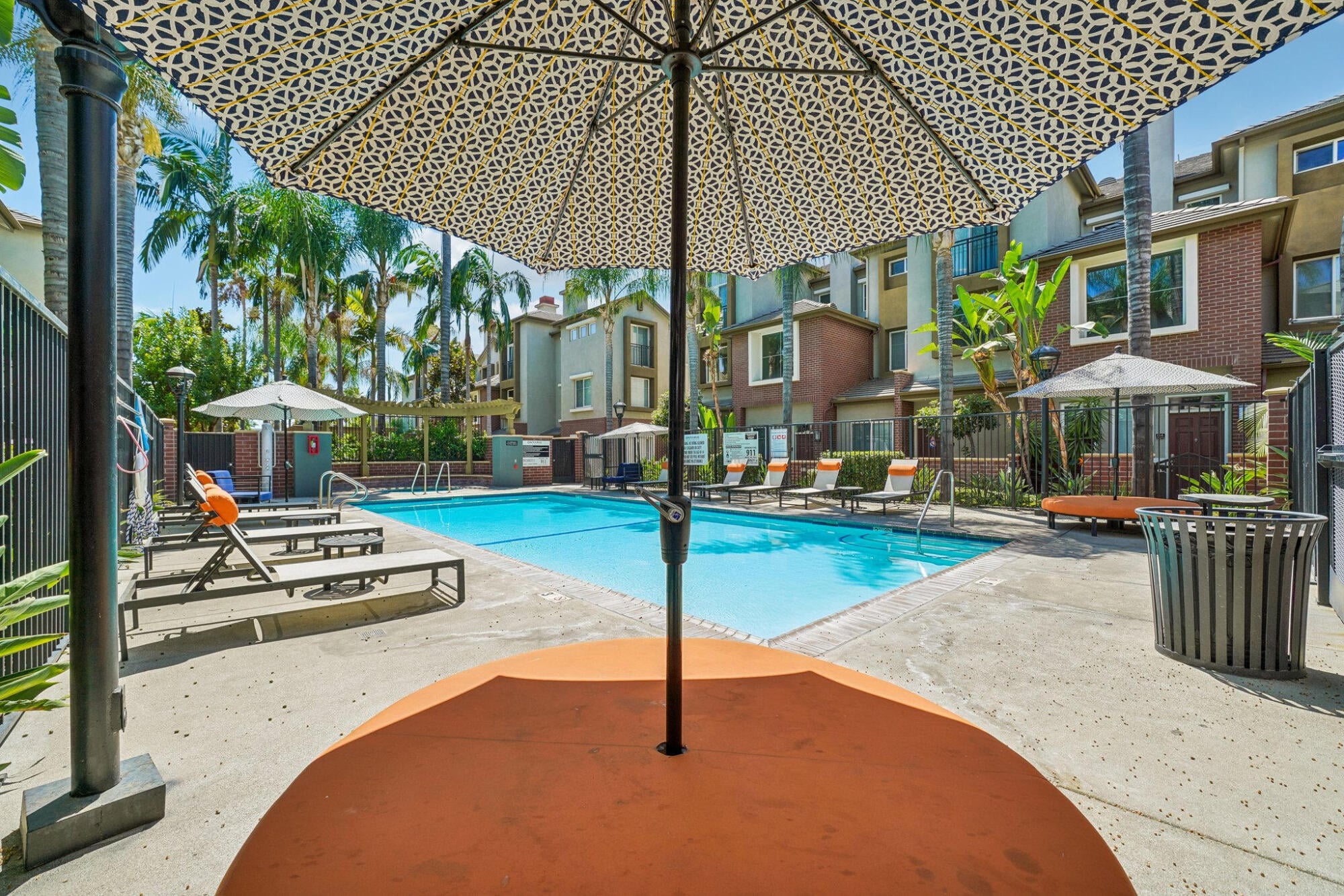 Shaded pool sundeck at Ontario Town Square Townhomes in Ontario, CA, with patio umbrellas and lounge seating.