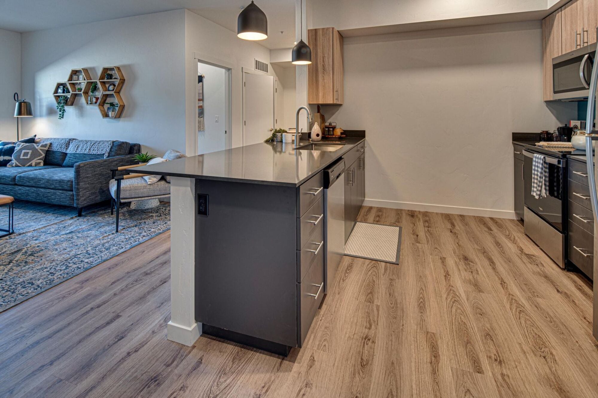 Model kitchen island opening onto the living room in a Cypress apartment home in Redmond, Oregon.