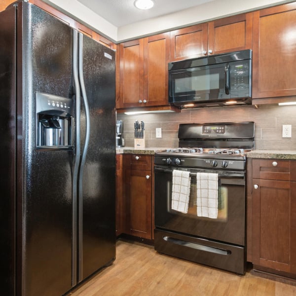 Townhome kitchen at Ontario Town Square Townhomes in Ontario, California, with full appliance package and rich wood cabinetry.