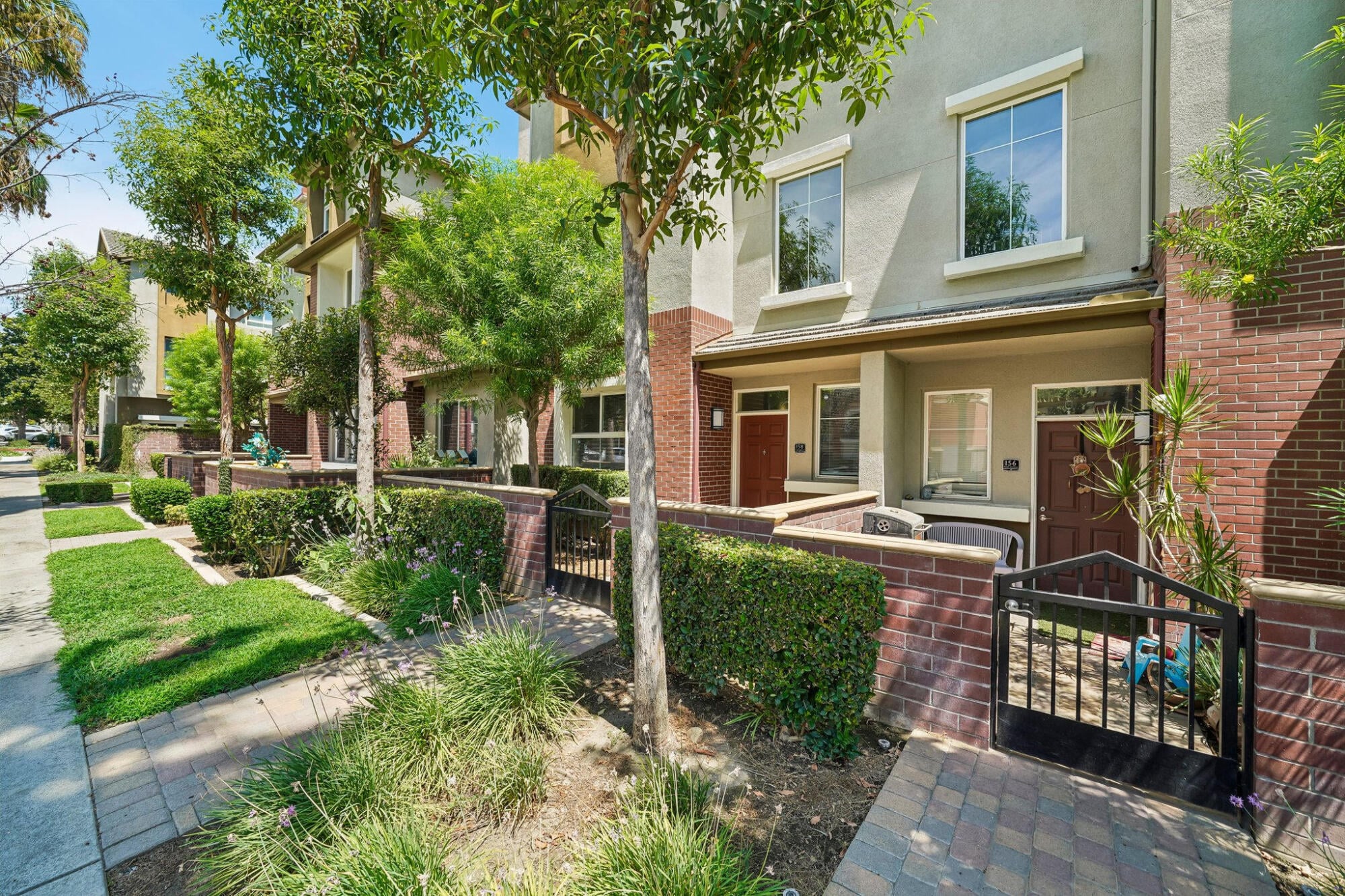 Community sidewalk running past gated townhome entries at Ontario Town Square Townhomes in Ontario, California.