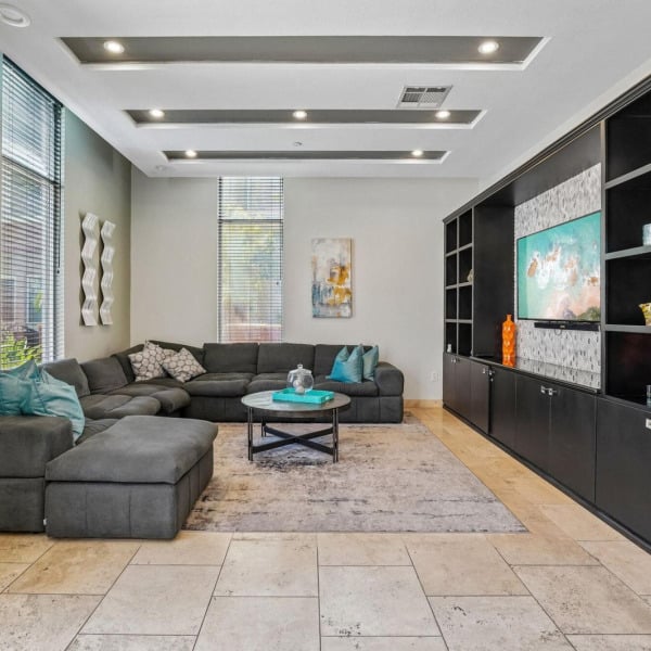 Clubhouse lounge at Ontario Town Square Townhomes in Ontario, CA, featuring a large sectional sofa and built-in media shelving.