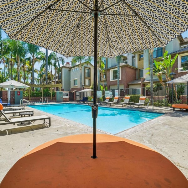 Shaded pool sundeck at Ontario Town Square Townhomes in Ontario, CA, with patio umbrellas and lounge seating.