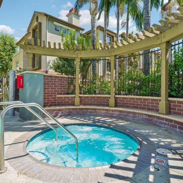 Hot tub with a brick surround and pergola shade at Ontario Town Square Townhomes in Ontario, CA.