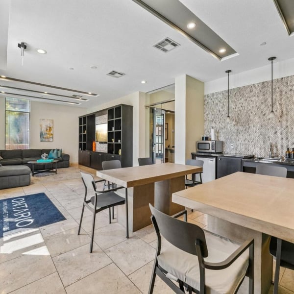 Clubhouse interior at Ontario Town Square Townhomes in Ontario, California, combining lounge seating, a community table, and a coffee bar.