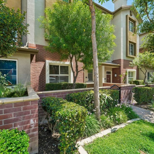Landscaped grounds and brick planters between the townhome buildings at Ontario Town Square Townhomes in Ontario, CA.