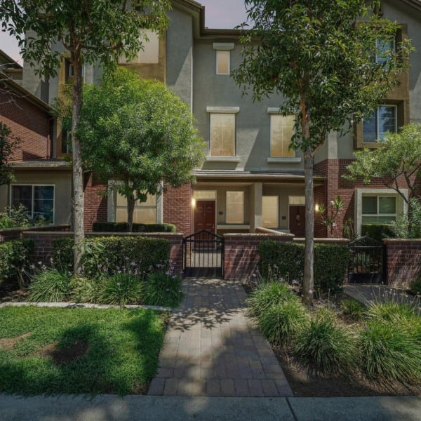 Landscaped townhome entrances at Ontario Town Square Townhomes in Ontario, CA, with brick planters and mature shade trees.