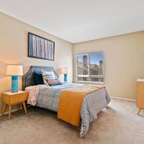 Carpeted bedroom in a townhome at Ontario Town Square Townhomes in Ontario, CA, with a bright window and generous closet space.
