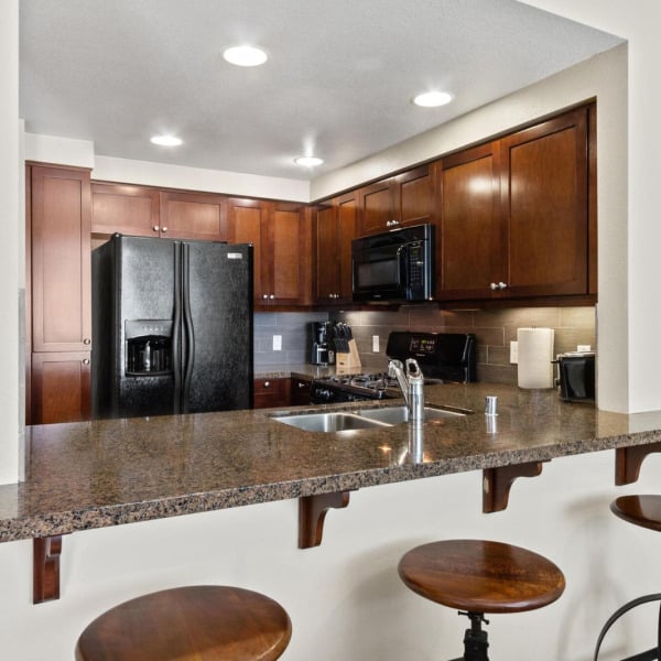 Granite breakfast bar with seating in a townhome kitchen at Ontario Town Square Townhomes in Ontario, California.