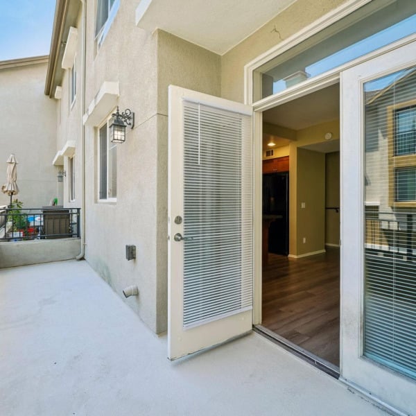 Private patio with sliding glass doors off the living area at Ontario Town Square Townhomes in Ontario, California.