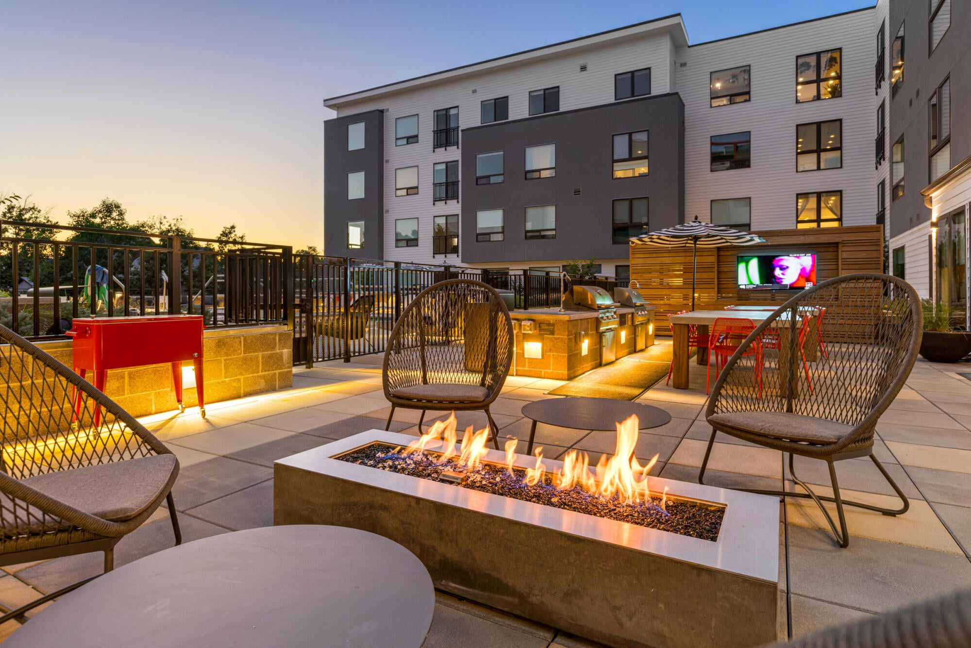 An outdoor firepit paired with a mounted TV lets residents gather outside at Jayne apartments in Denver, CO.