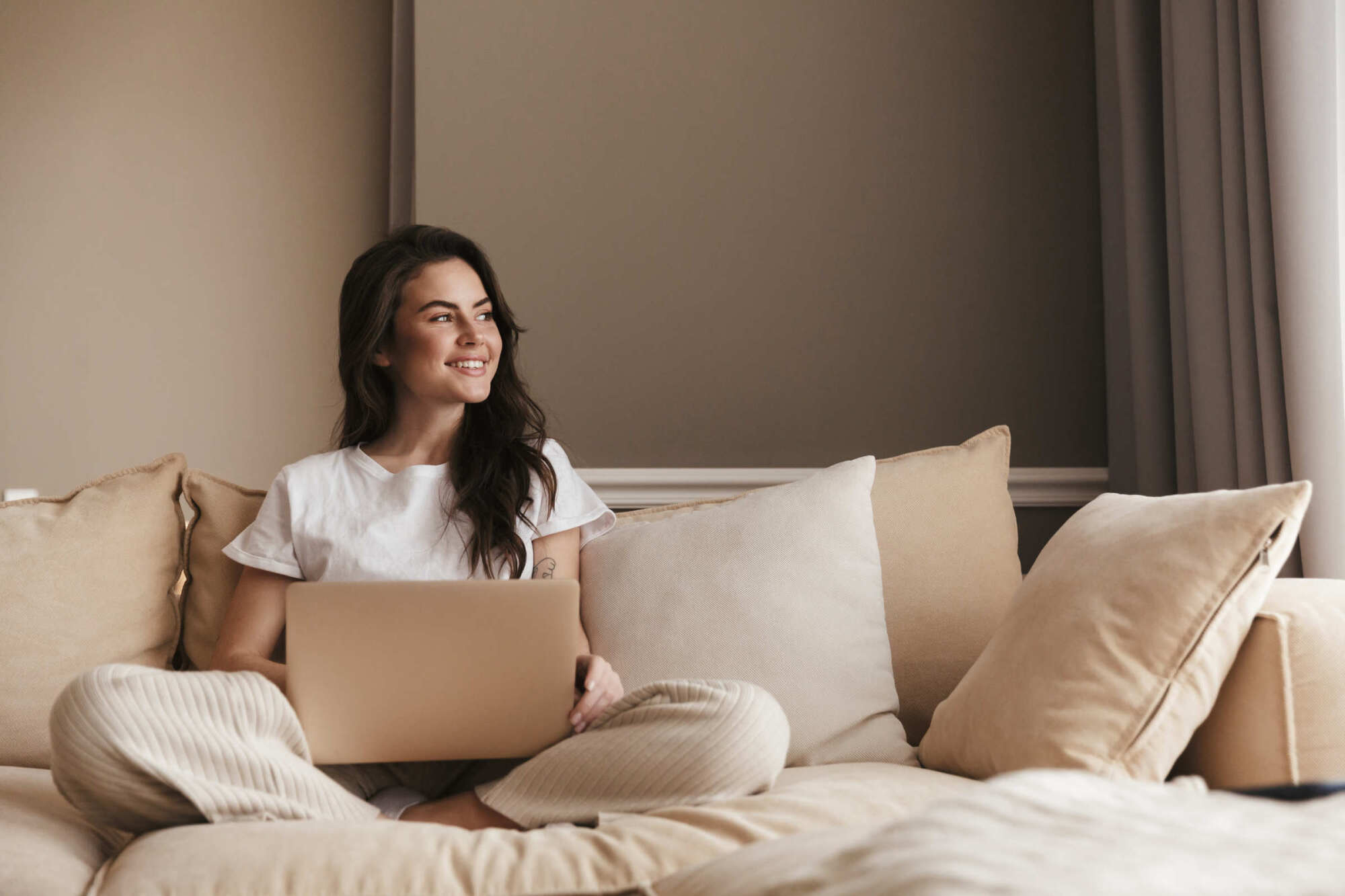 Ellwyn in Cottage Grove, Minnesota, lifestyle scene of a woman using a laptop while seated on a neutral-toned sofa.