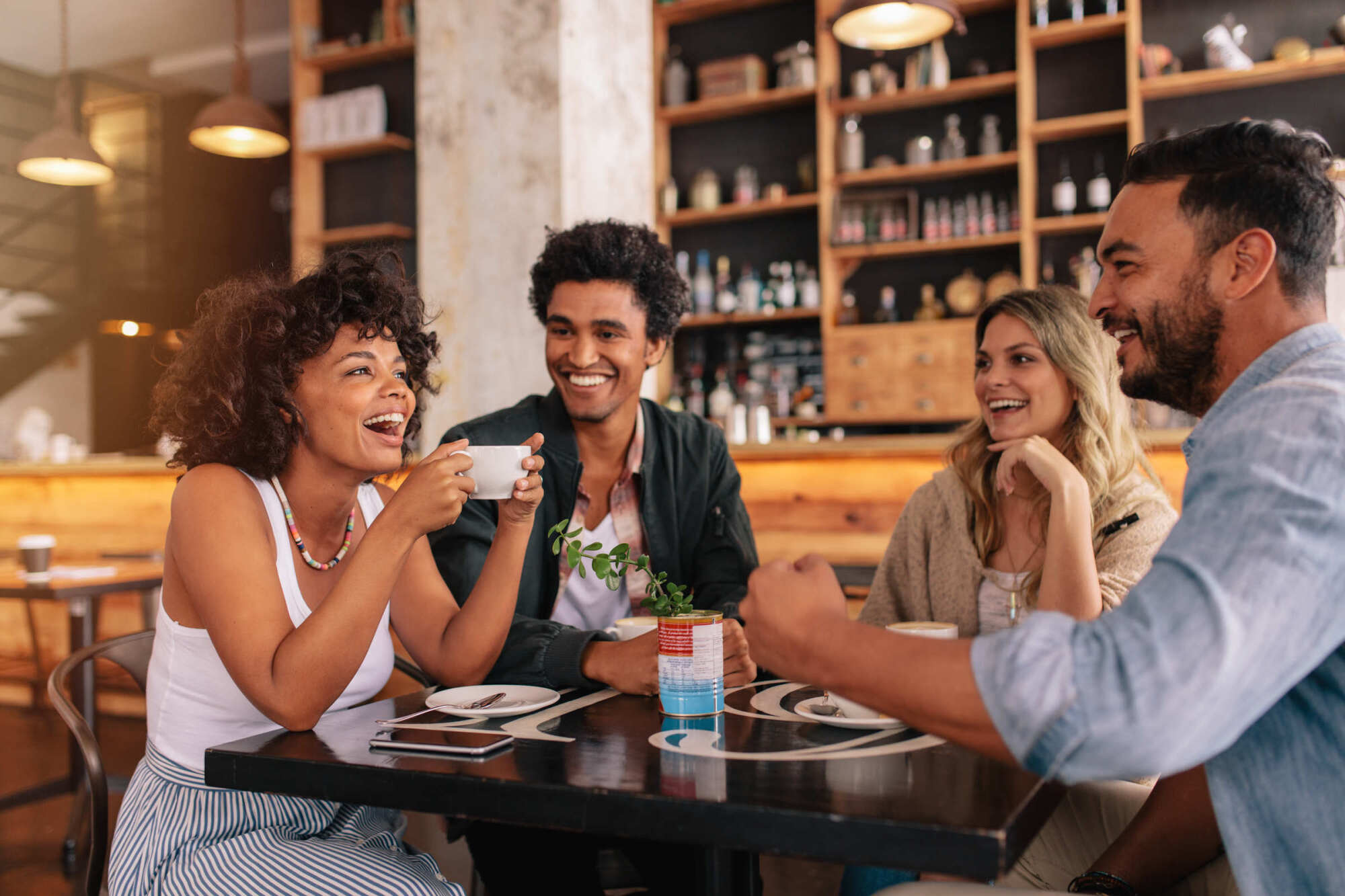 Lofts at Durham Park, Richmond, VA: lifestyle photo of four friends laughing together over drinks at a restaurant table.