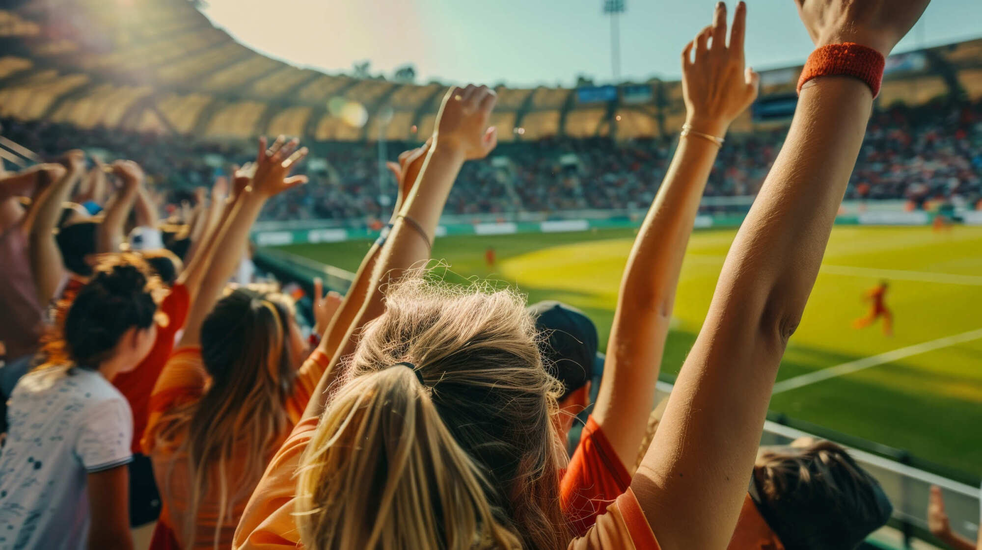 Lofts at Durham Park, Richmond, VA: lifestyle photo of spectators raising their arms toward a playing field in a crowded stadium.