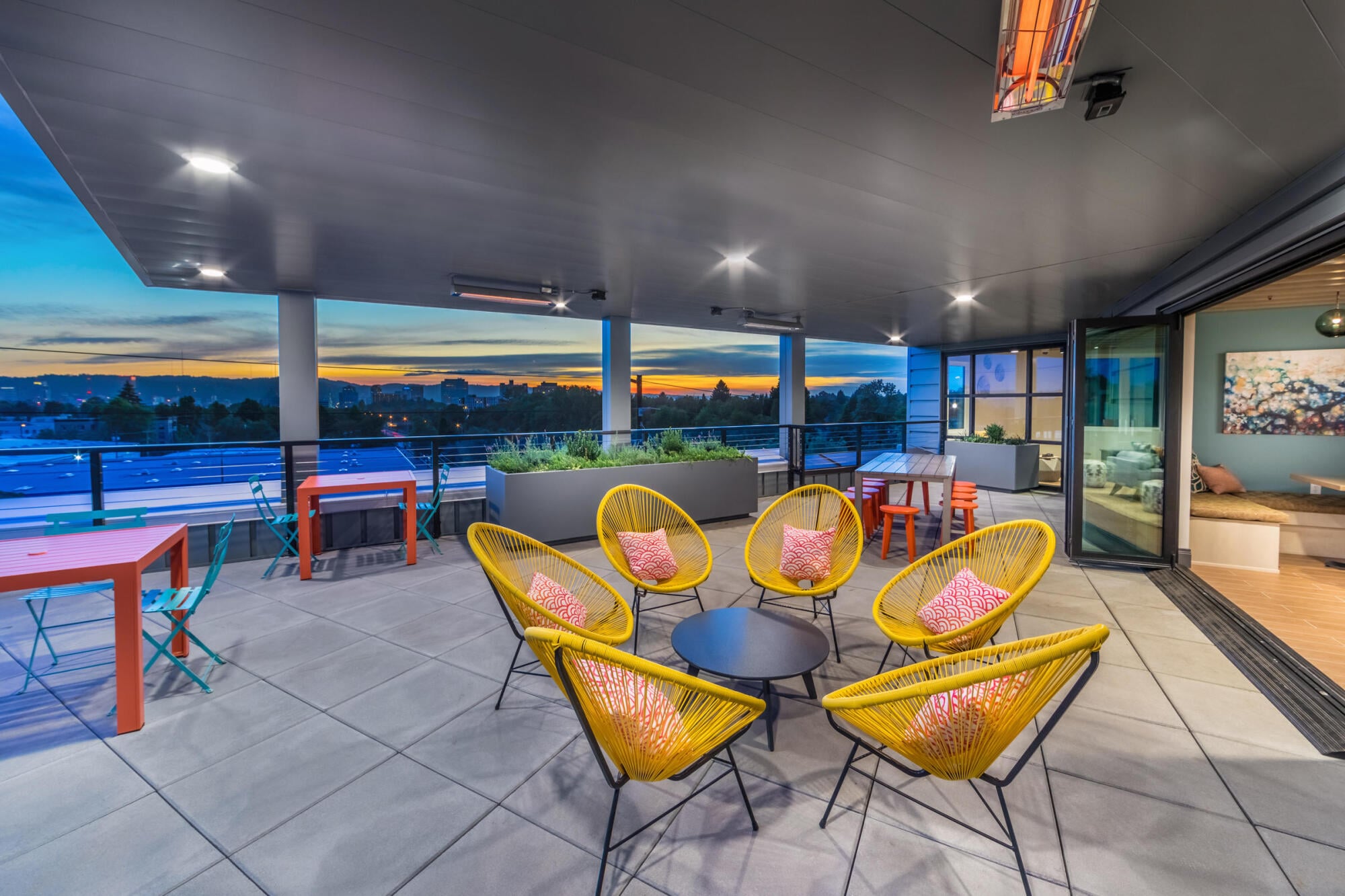 Sandy Lofts' rooftop lounge at dusk in Portland, OR, overlooking the Kerns neighborhood skyline as the sun sets.