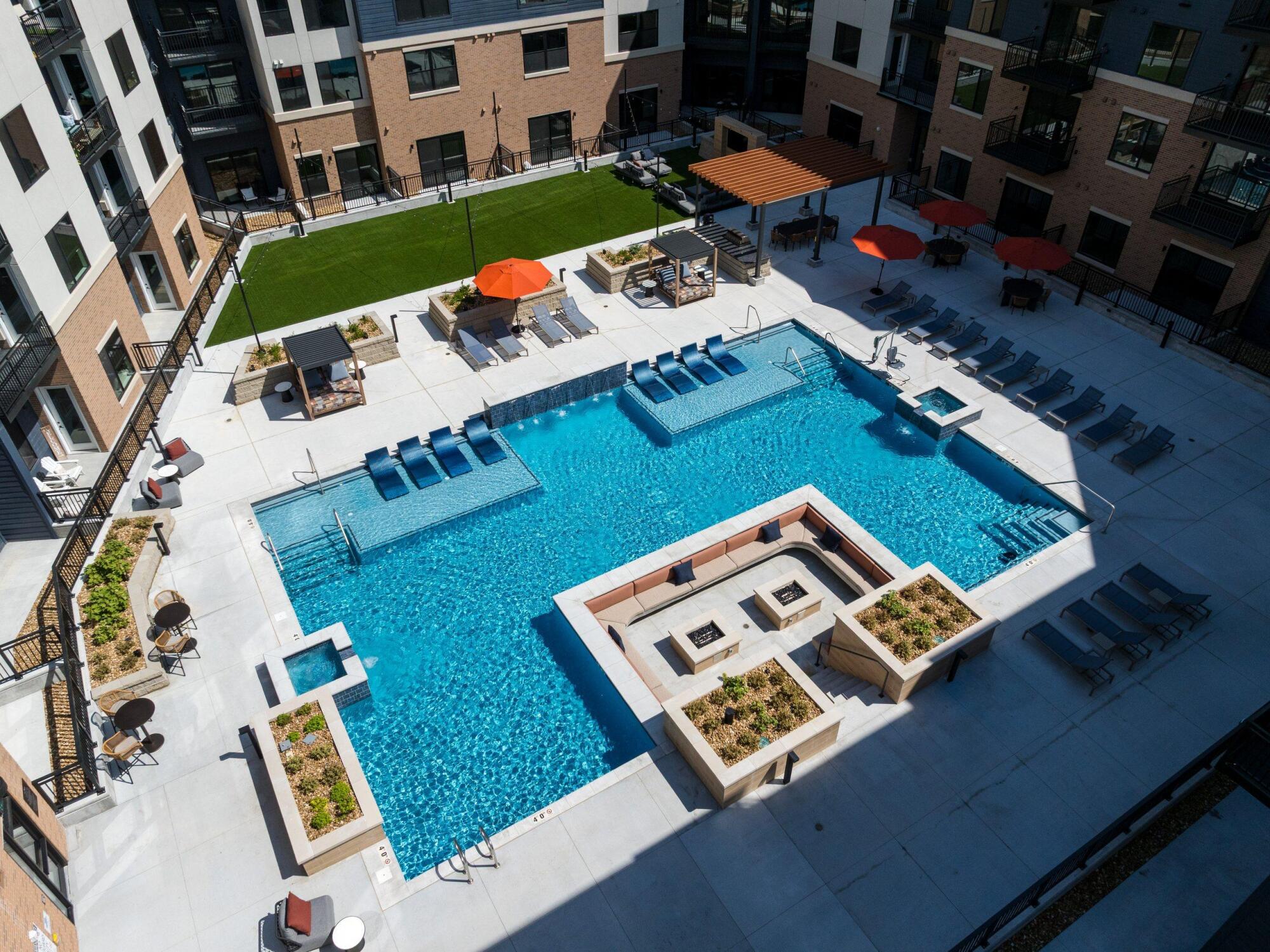 Overhead view of the pool courtyard with a sunken fire lounge, cabanas, loungers, planters and a turf lawn