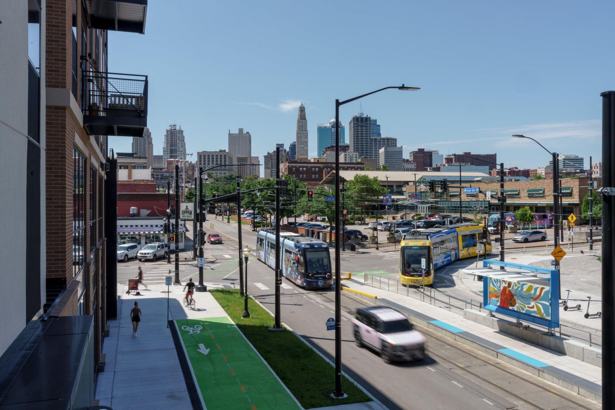 View down Grand Boulevard of the KC Streetcar, a protected bike lane and the downtown Kansas City skyline