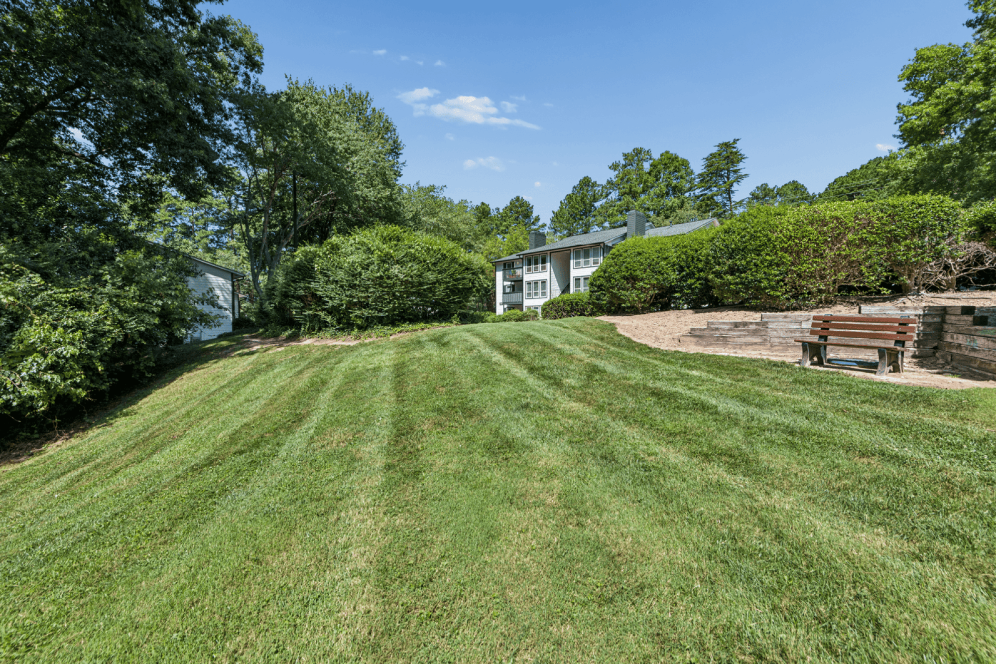 A large, well-maintained lawn leads to a house.