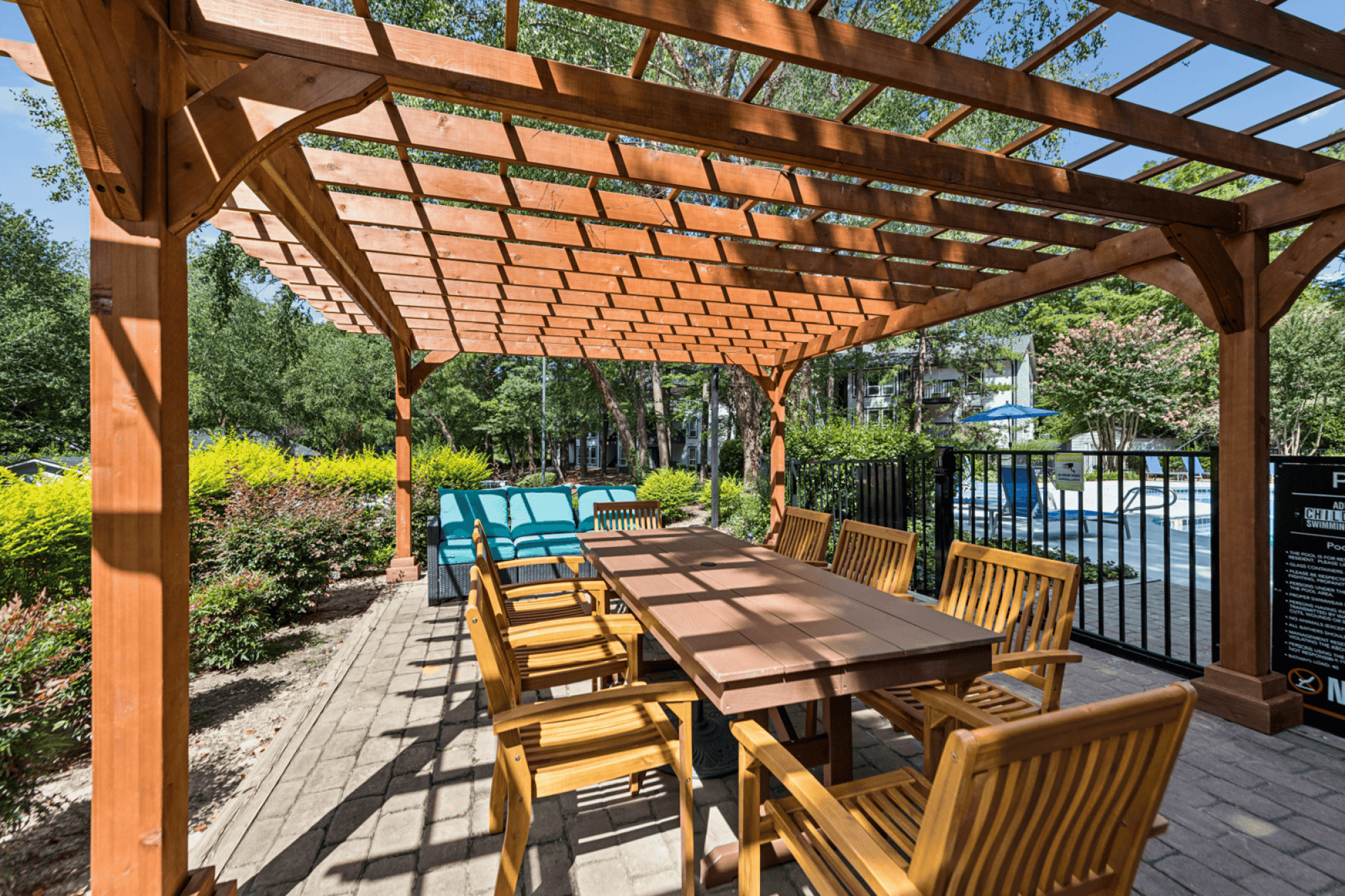 A wooden pergola with a table and chairs underneath it.