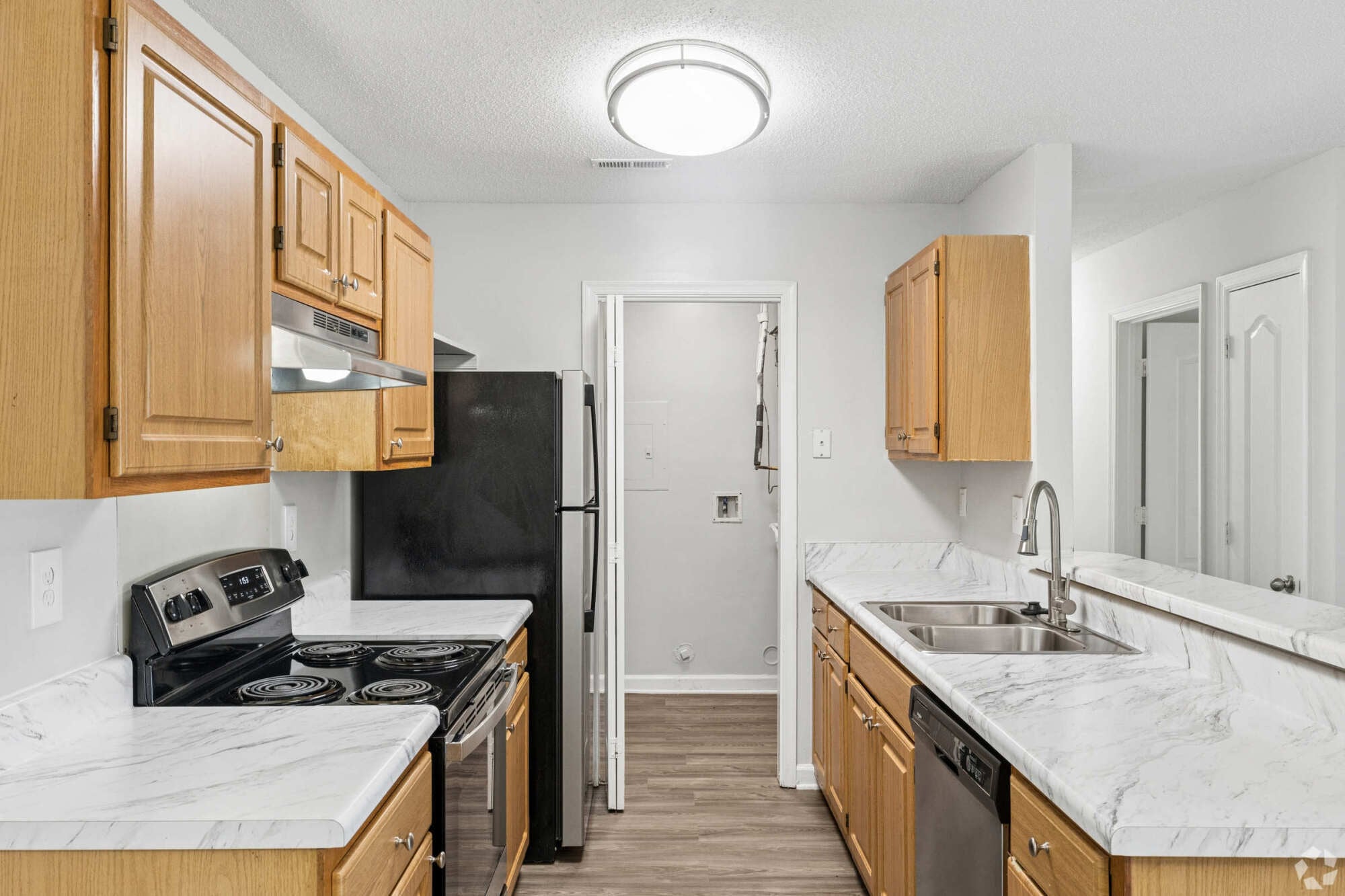 Oaks of Dunlop Farms in Colonial Heights, VA, kitchen with wood cabinets, white countertops, a double sink, and a range.