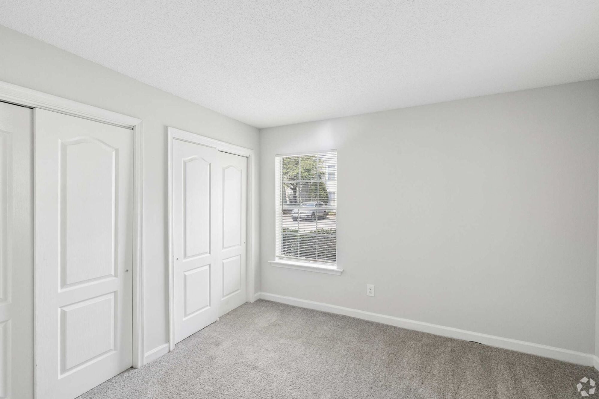 Oaks of Dunlop Farms in Colonial Heights, VA, bedroom with carpet, two closets, and a window with blinds.